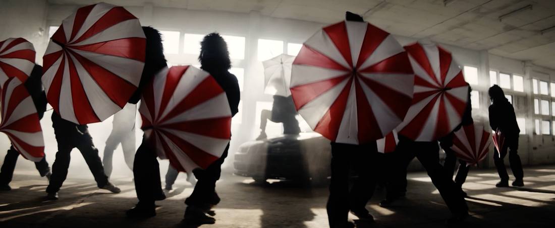 Red-and-white umbrellas spinning in a foggy warehouse